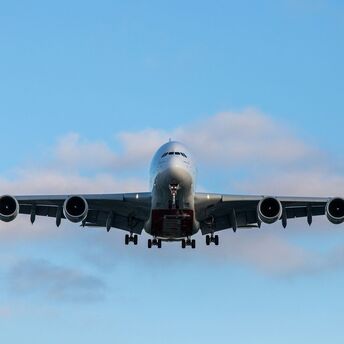 Front view of a large passenger airplane approaching for landing against a blue sky