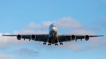 Front view of a large passenger airplane approaching for landing against a blue sky