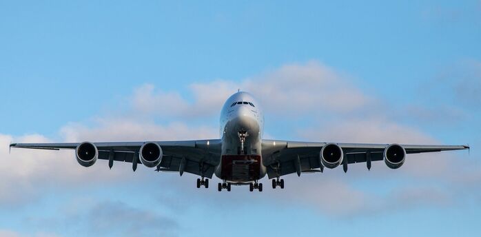 Front view of a large passenger airplane approaching for landing against a blue sky