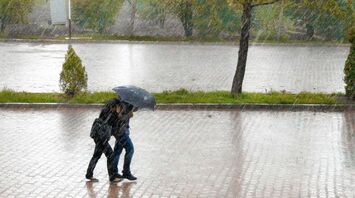 Travellers walking through heavy rain under an umbrella
