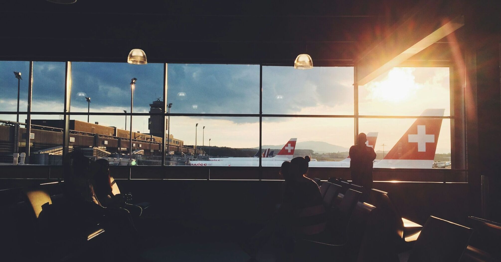 Passengers waiting at Zurich Airport as aircraft prepare for departure at sunset