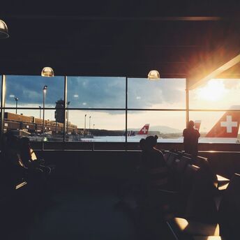 Passengers waiting at Zurich Airport as aircraft prepare for departure at sunset