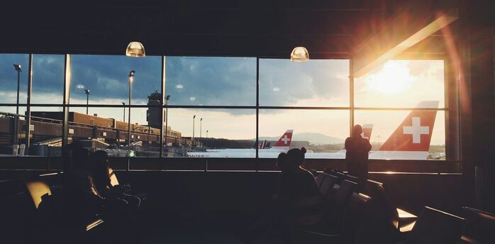 Passengers waiting at Zurich Airport as aircraft prepare for departure at sunset