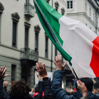 Crowd in Italy raising hands during public action with Italian flag