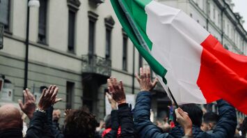 Crowd in Italy raising hands during public action with Italian flag