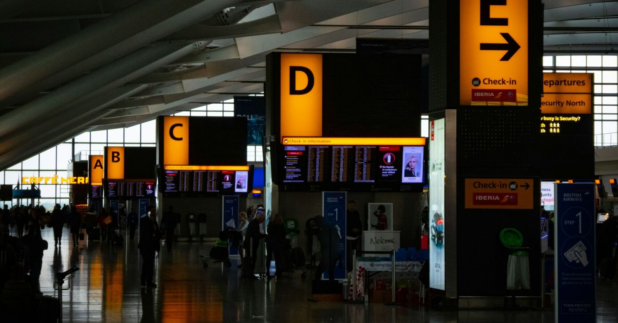 Passengers moving through a busy Heathrow airport terminal
