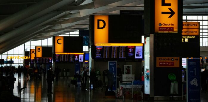 Passengers moving through a busy Heathrow airport terminal