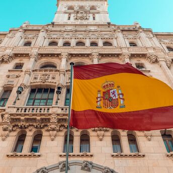 Spanish flag waving outside a historic building in Madrid