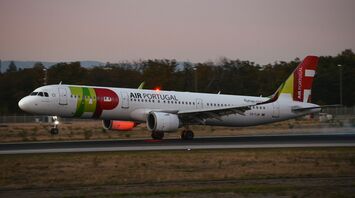 Air Portugal aircraft touching down on the runway at dusk