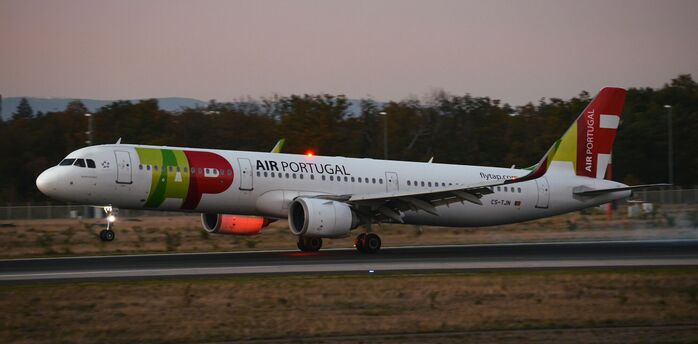 Air Portugal aircraft touching down on the runway at dusk