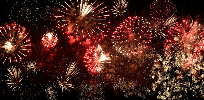 Multiple red and gold fireworks bursting in the night sky