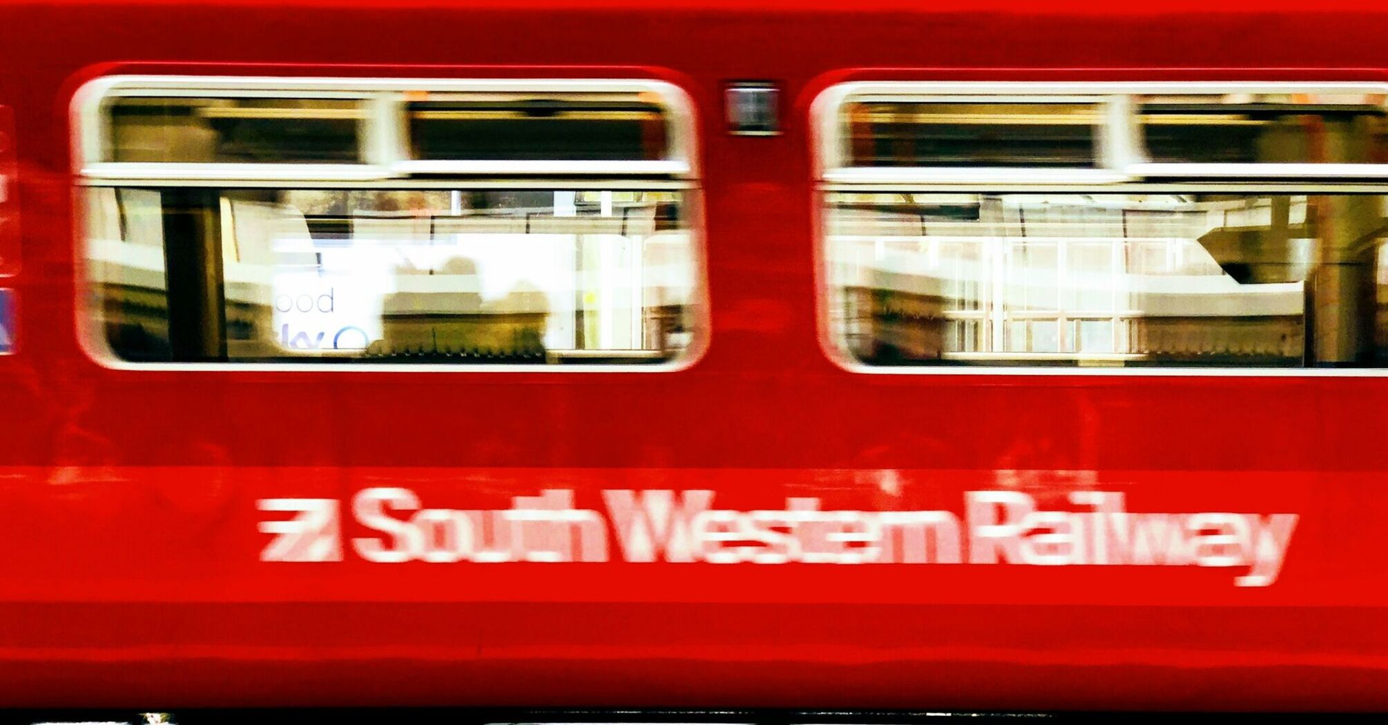 Red South Western Railway train passing through a station platform