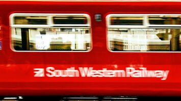 Red South Western Railway train passing through a station platform