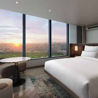 Hotel room with large windows overlooking Manila at sunset