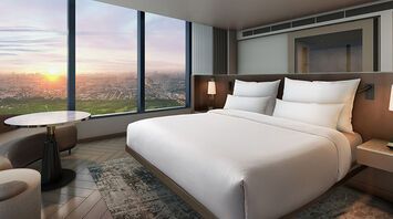 Hotel room with large windows overlooking Manila at sunset