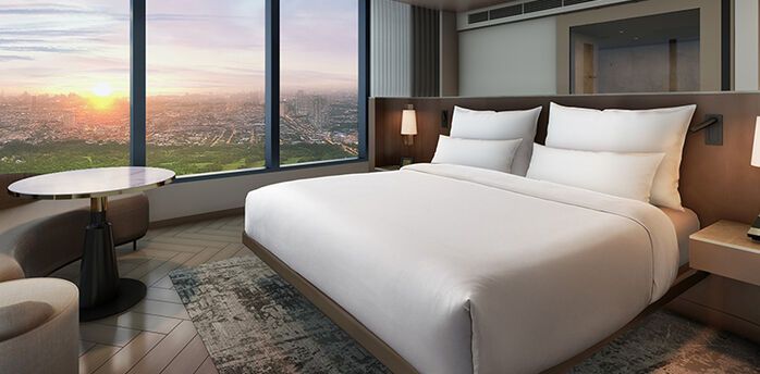 Hotel room with large windows overlooking Manila at sunset