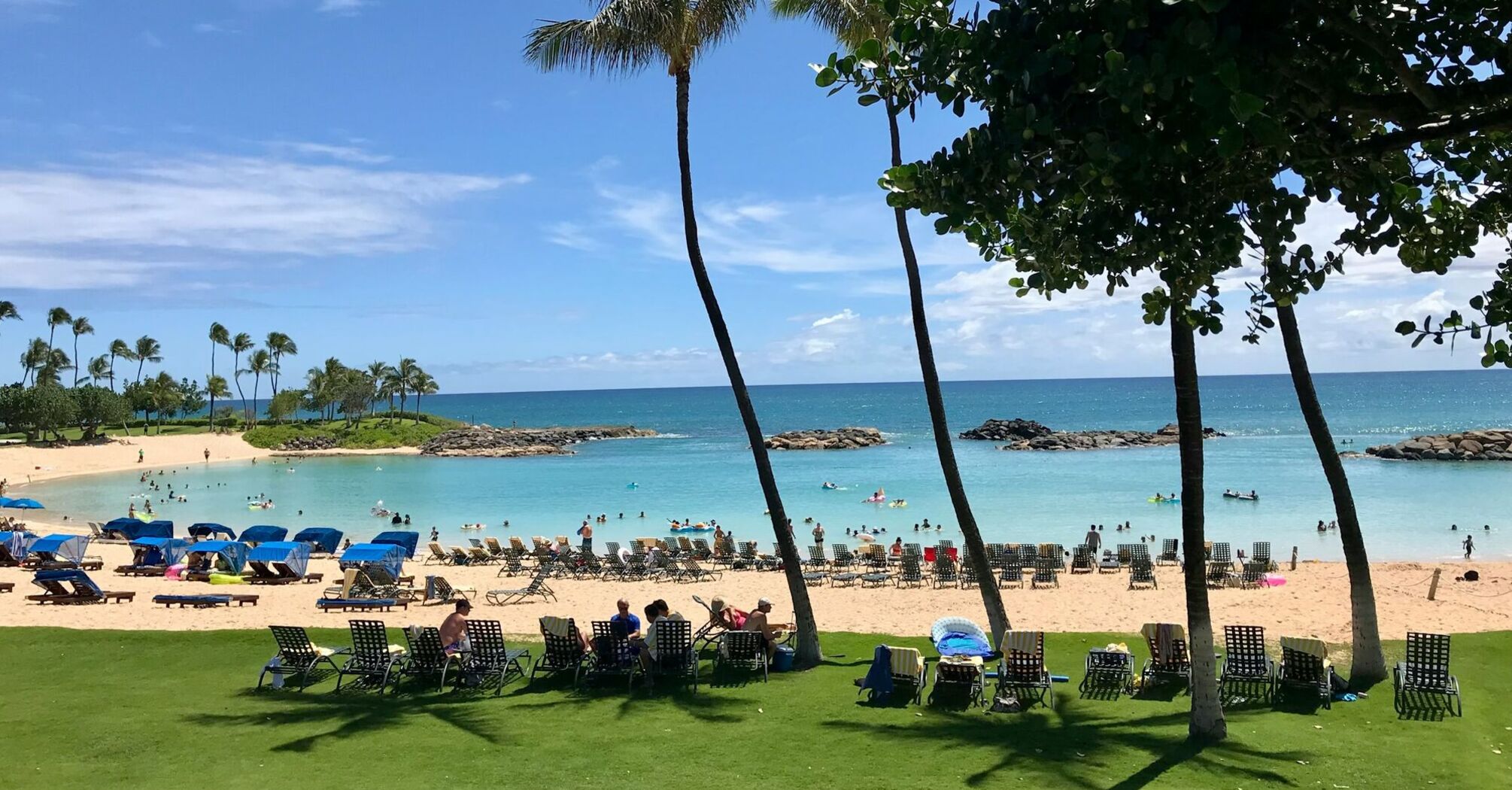 Crowded beach in Hawaii with visitors relaxing near the ocean on a sunny day