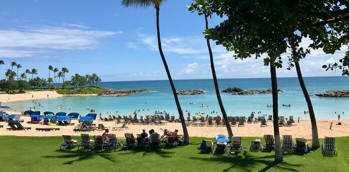 Crowded beach in Hawaii with visitors relaxing near the ocean on a sunny day