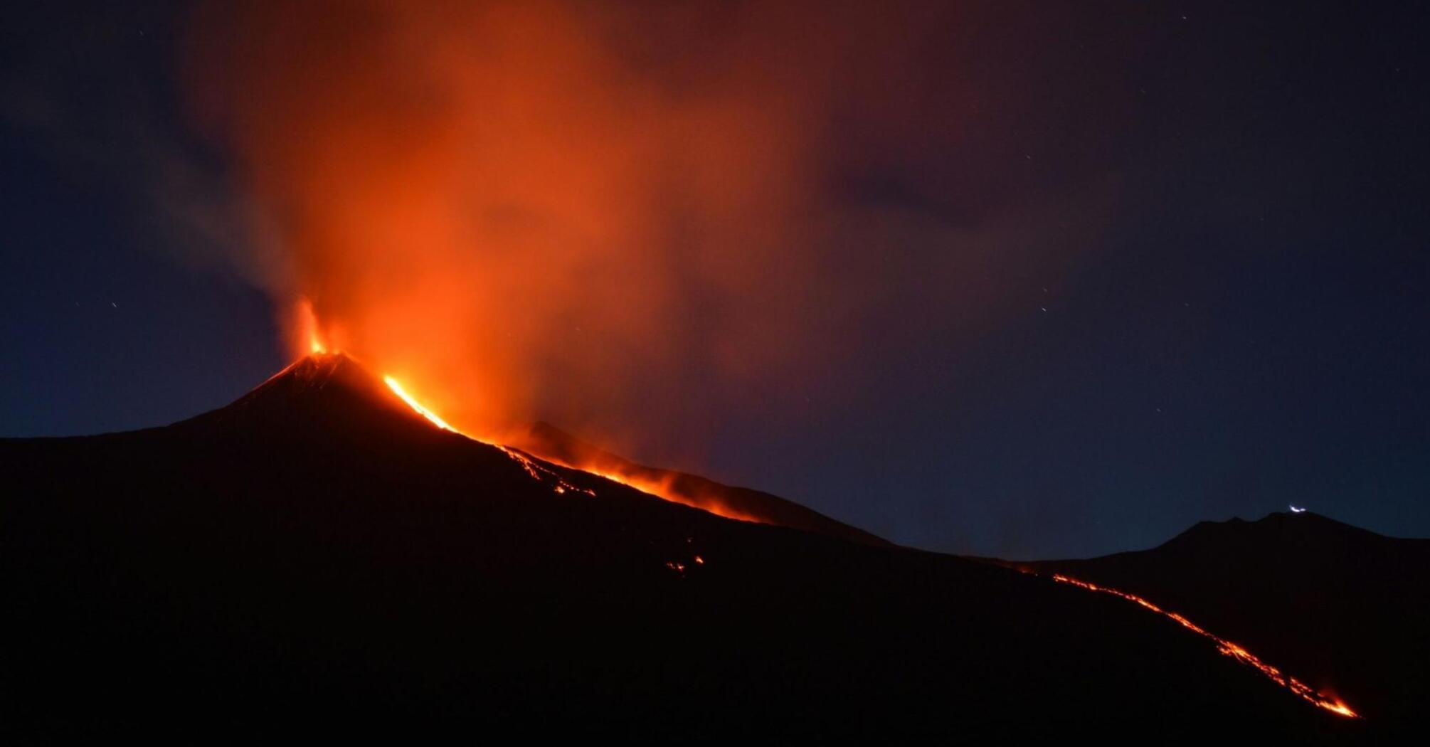 Lava and ash erupting from Mount Etna at night. 