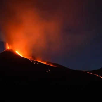 Lava and ash erupting from Mount Etna at night.