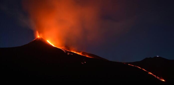 Lava and ash erupting from Mount Etna at night.