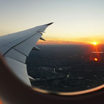 Airplane wing and sunset view through the window