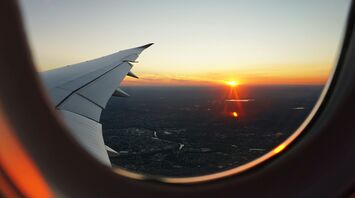Airplane wing and sunset view through the window