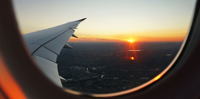 Airplane wing and sunset view through the window