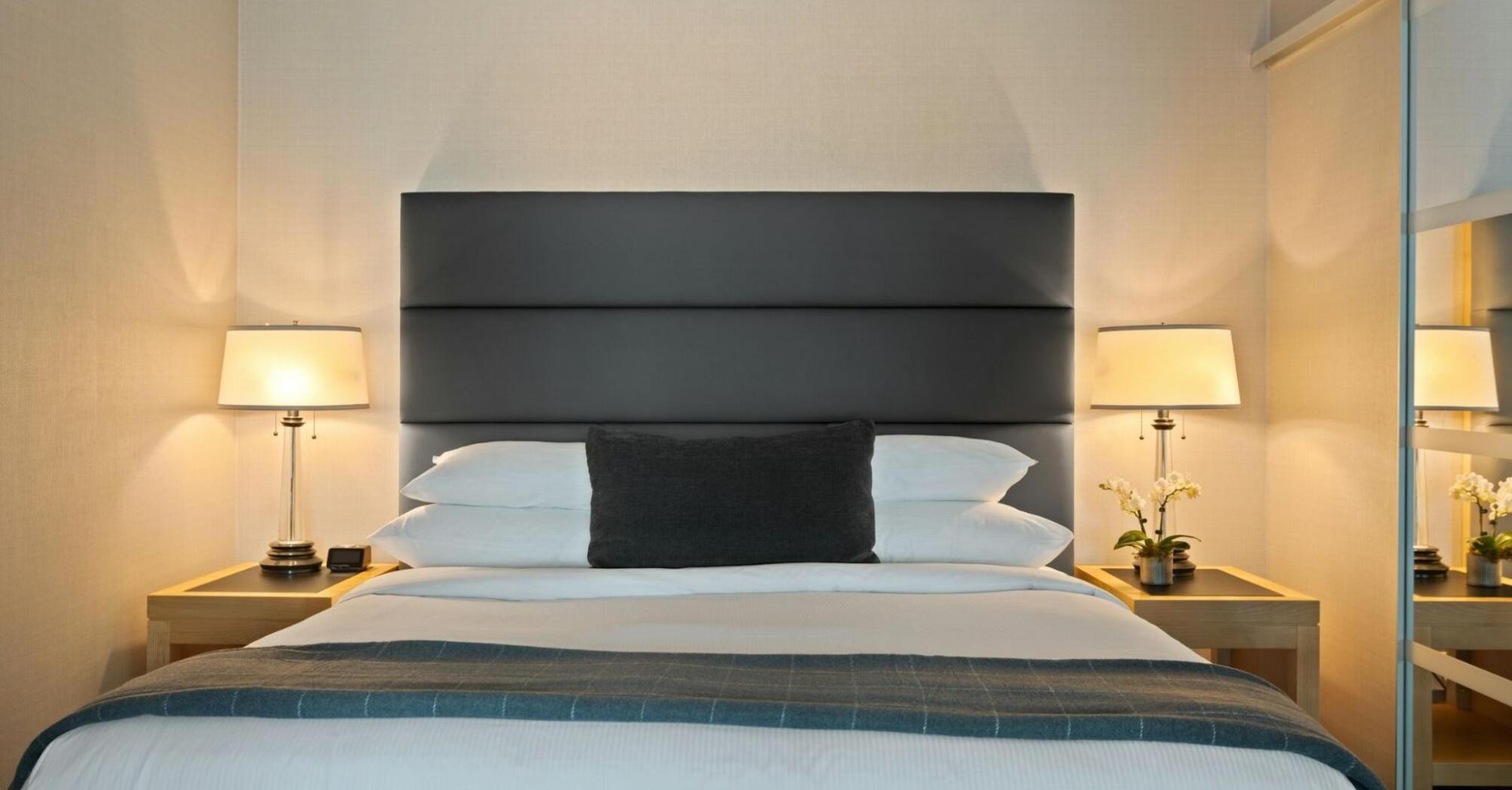 Modern hotel room with soft lighting and a neatly arranged bed