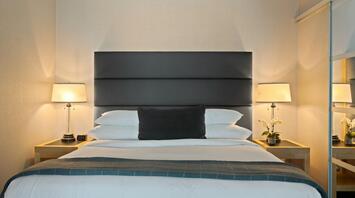 Modern hotel room with soft lighting and a neatly arranged bed