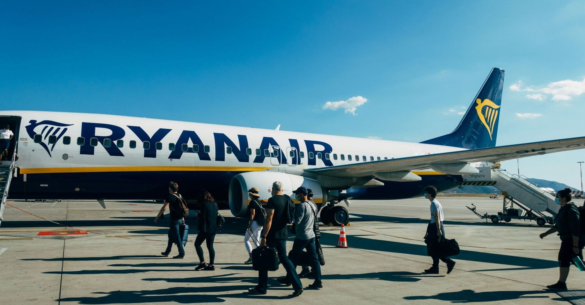 Passengers boarding a Ryanair aircraft on the tarmac under clear blue skies