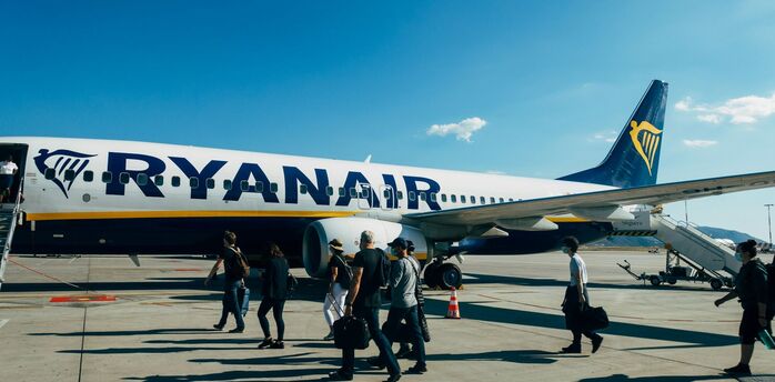Passengers boarding a Ryanair aircraft on the tarmac under clear blue skies