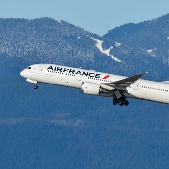 Air France aircraft climbing after take-off with mountain scenery behind