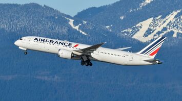 Air France aircraft climbing after take-off with mountain scenery behind