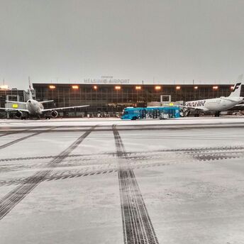 Snow-covered aircraft and buses on the Helsinki Airport apron during winter operations