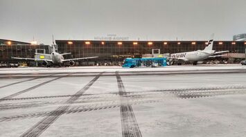 Snow-covered aircraft and buses on the Helsinki Airport apron during winter operations