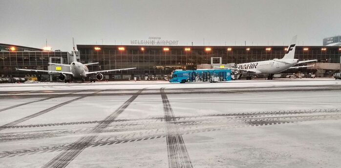 Snow-covered aircraft and buses on the Helsinki Airport apron during winter operations