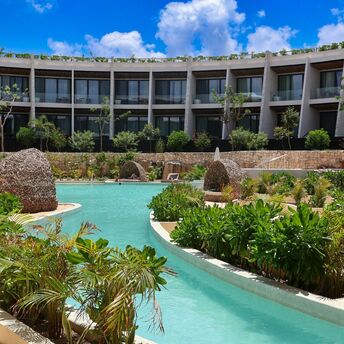 Resort pool surrounded by tropical plants and guest suites