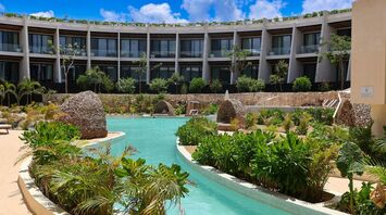 Resort pool surrounded by tropical plants and guest suites