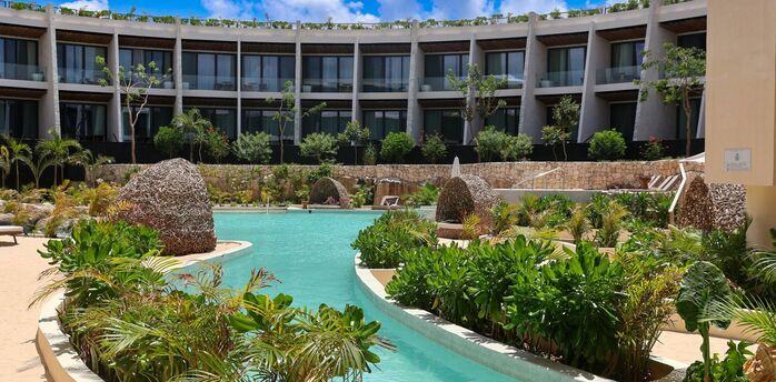 Resort pool surrounded by tropical plants and guest suites