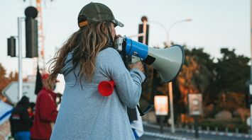 A woman with a megaphone leading a protest on a city street