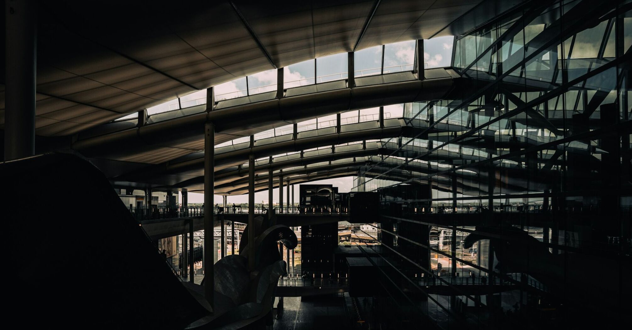 Modern interior of a UK airport terminal with glass walls and a curved ceiling allowing natural light inside