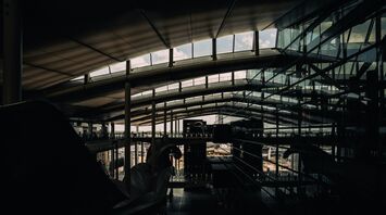 Modern interior of a UK airport terminal with glass walls and a curved ceiling allowing natural light inside