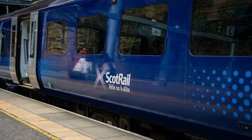 A ScotRail train at a station platform with passengers visible through the windows