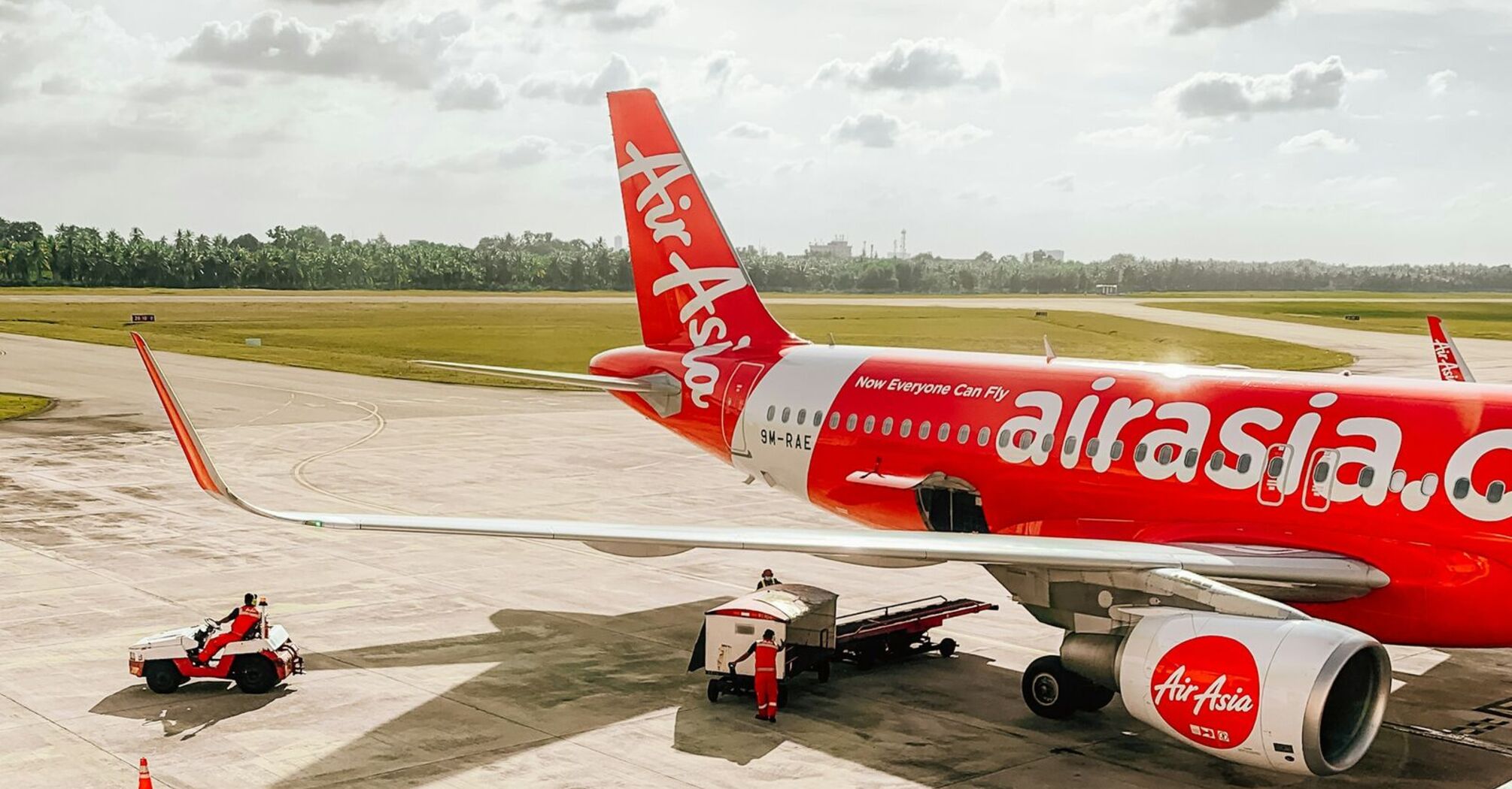 AirAsia aircraft on the tarmac with ground crew and support vehicles at an airport