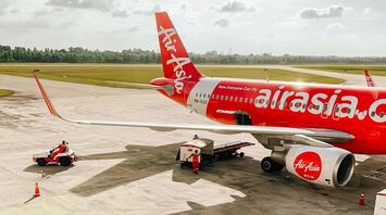 AirAsia aircraft on the tarmac with ground crew and support vehicles at an airport