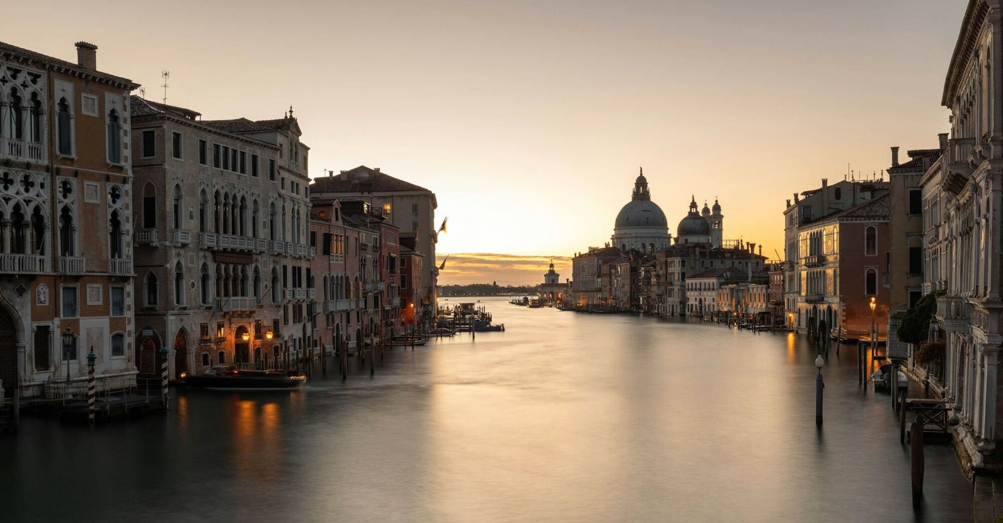 Grand Canal in Venice at sunset with historic buildings and Basilica di Santa Maria della Salute in the background