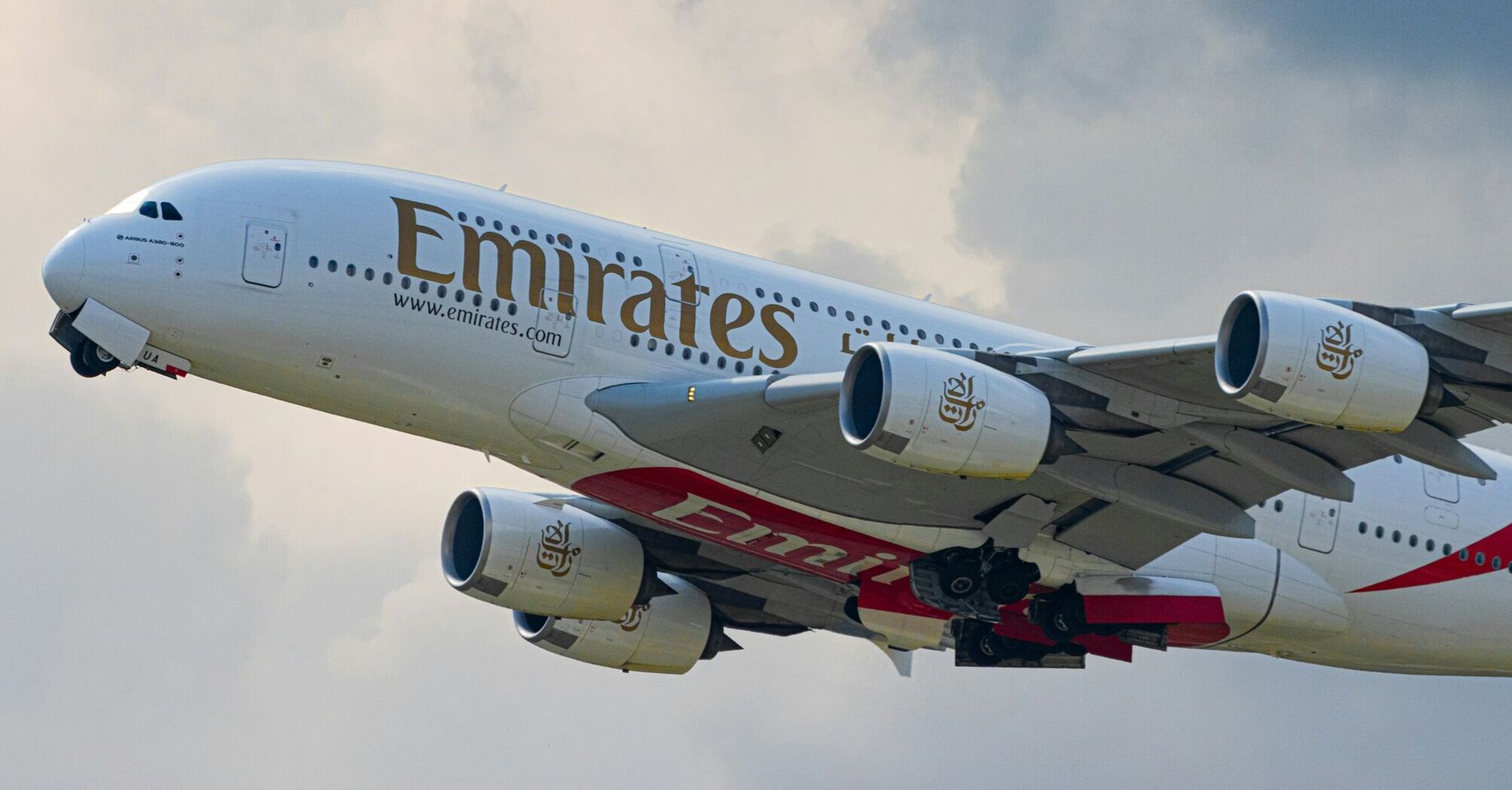 Emirates Airbus A380 taking off against a cloudy sky