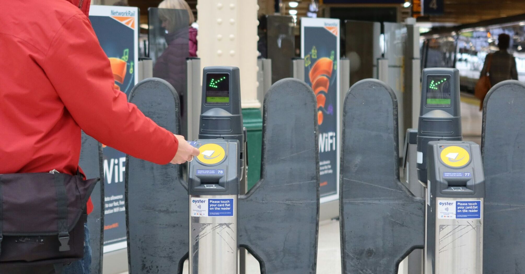 Person tapping a card at a train station gate