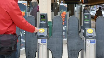 Person tapping a card at a train station gate
